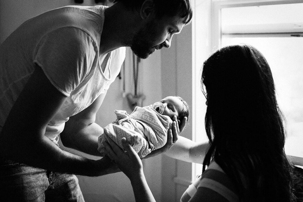 new parents handing baby to each other